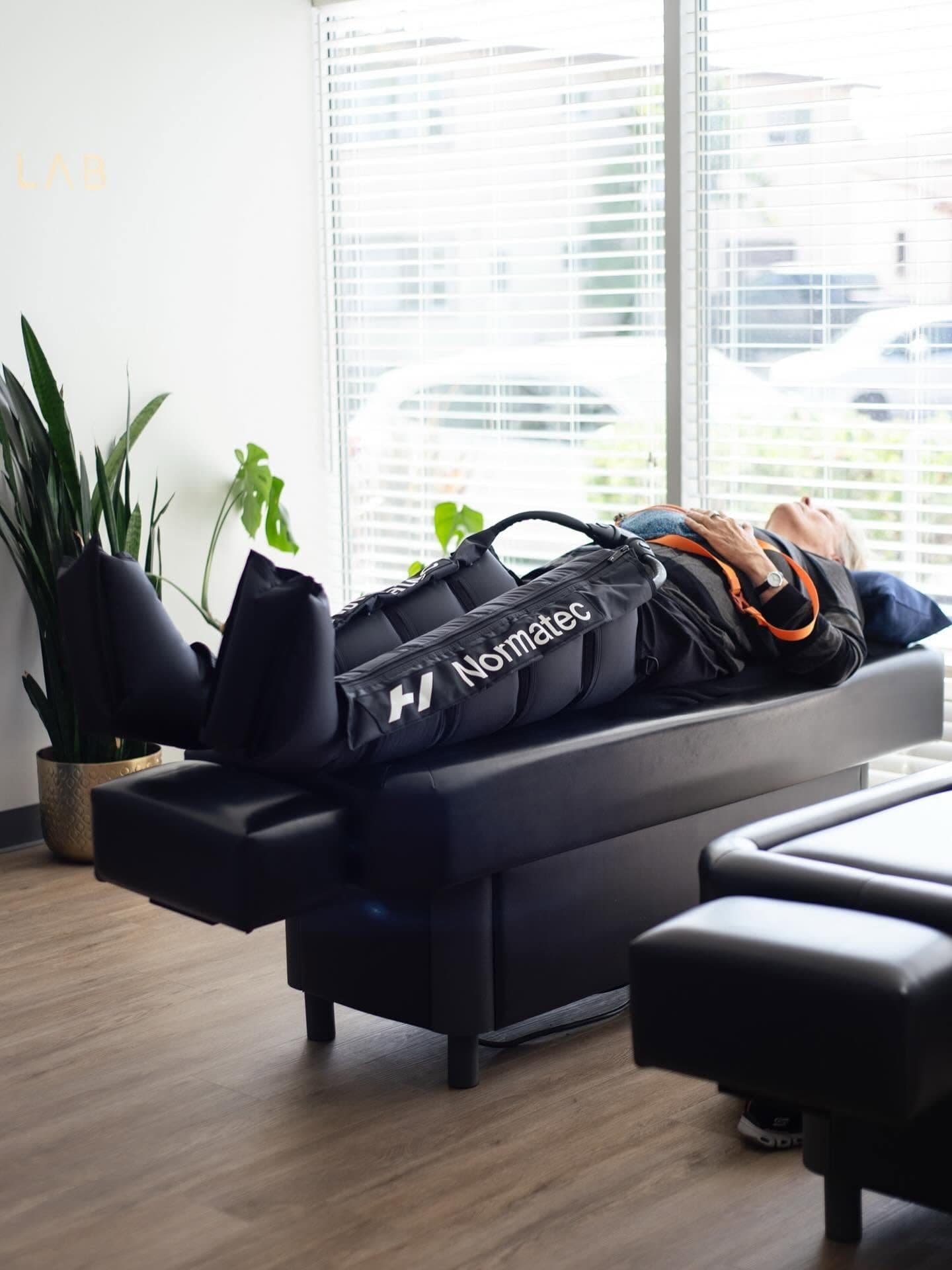 A patient relaxing in Normatec compression recovery boots at Element Wellness Center