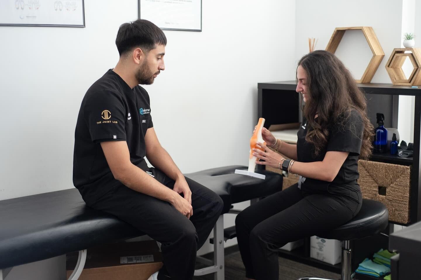 An Element Wellness Center team member using a knee joint model to explain treatment during a consultation