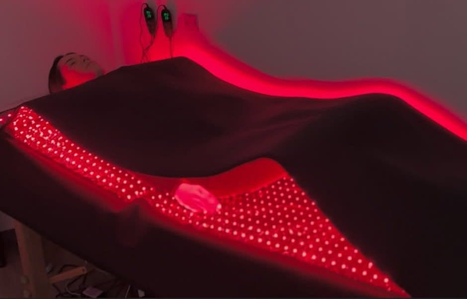 A patient resting under red light therapy panels during a session at Element Wellness Center