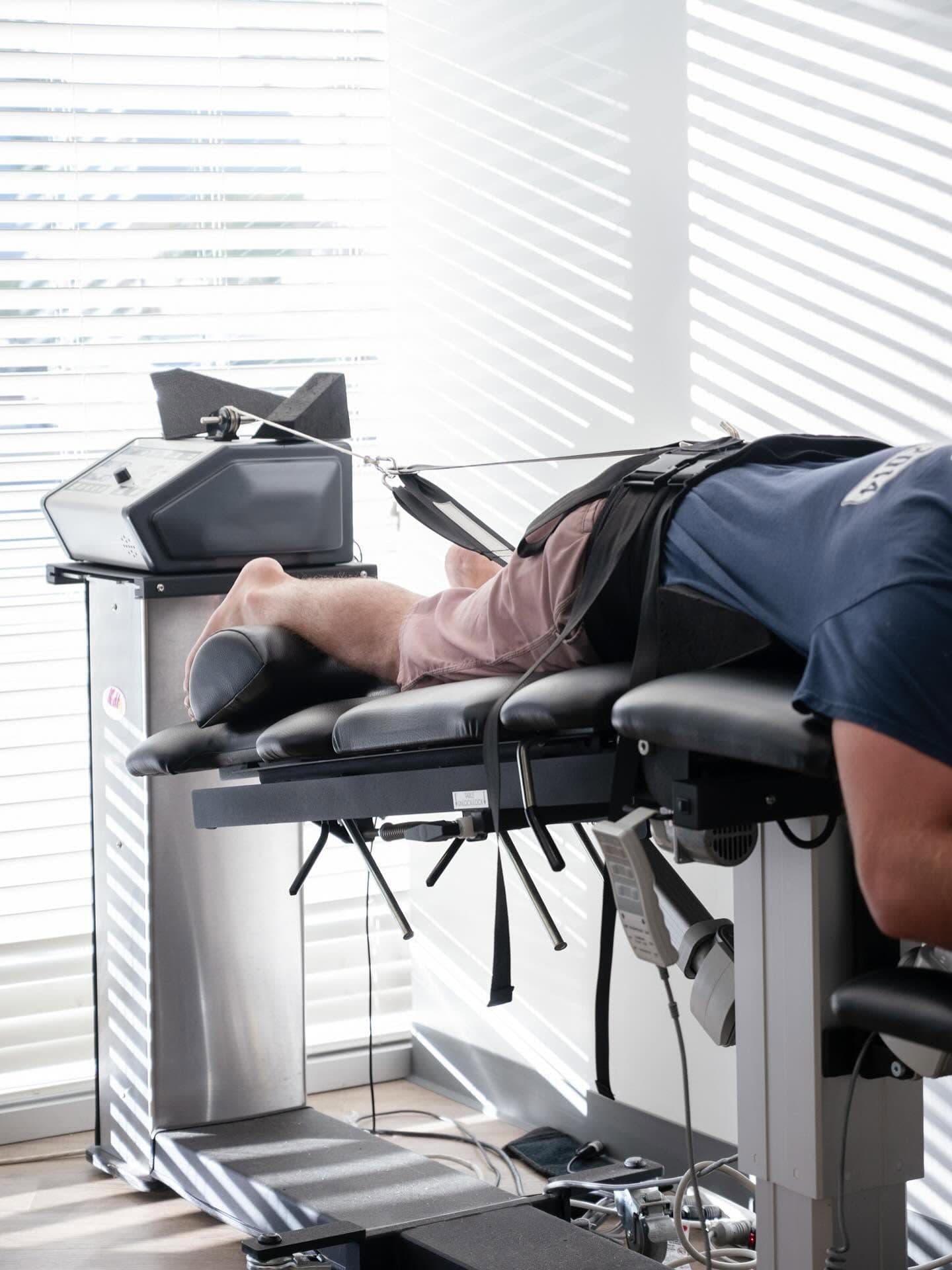 A patient receiving non-surgical spinal decompression therapy on a motorized traction table at Element Wellness Center